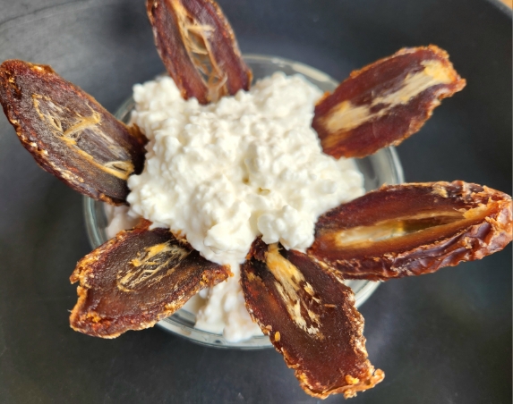 cottage cheese in small glass bowl with dried and sliced dates slides dipped in
