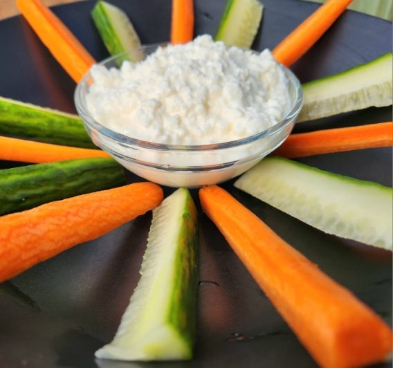cottage cheese in small glass bowl with carrot and cucumber slices around it