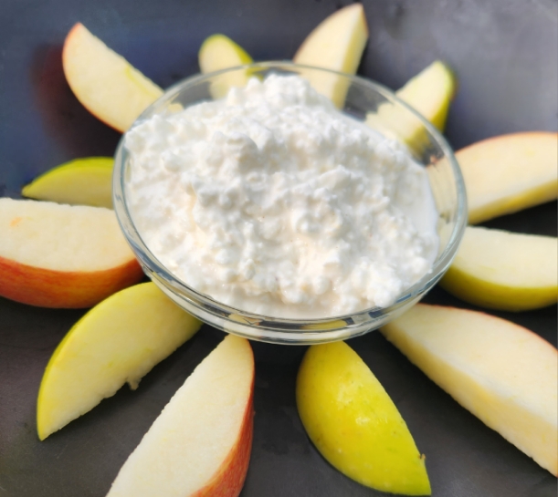 cottage cheese in small glass bowl with apple slices around it