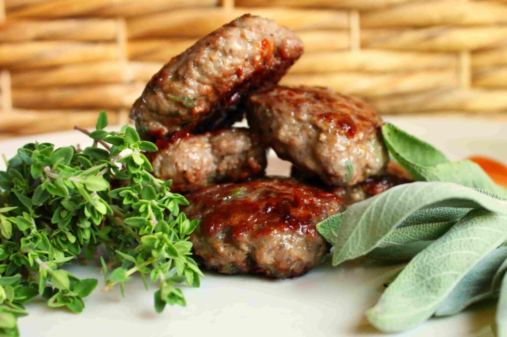 stack of elk breakfast sausage patties on plate with herbs