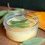 beard butter in glass container with wooden comb and herbs