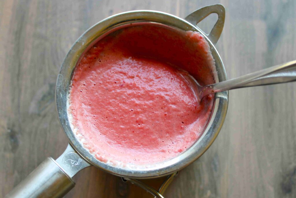 straining beet milk through fine mesh sieve
