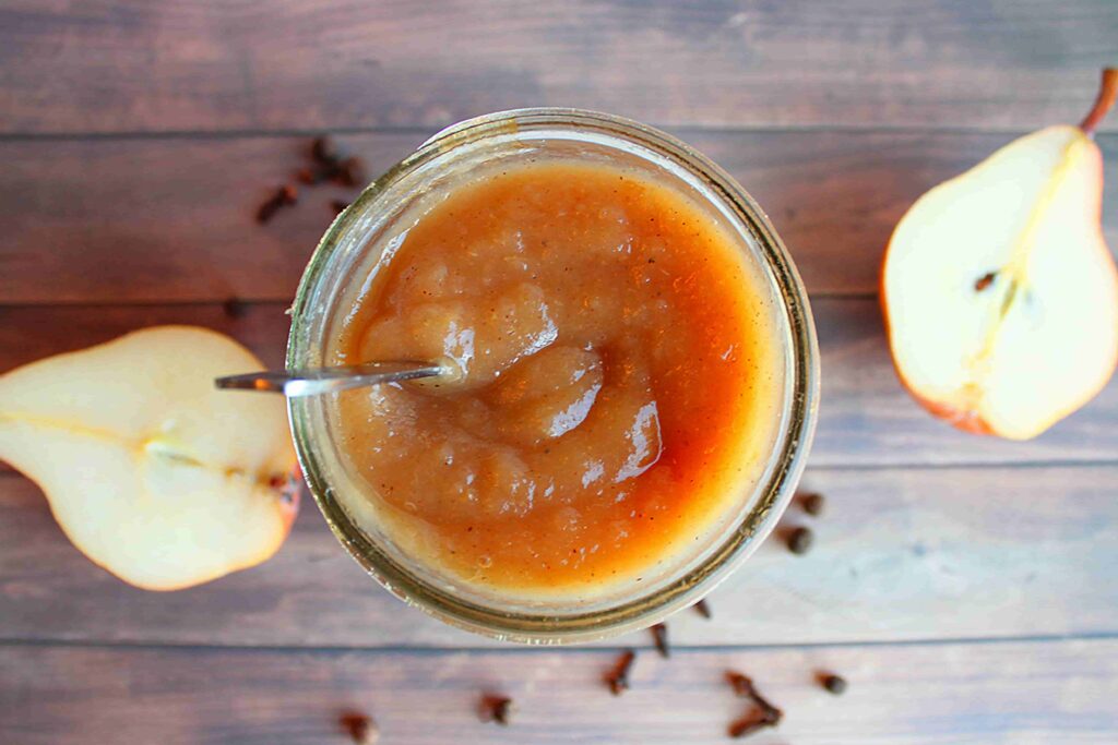 pear butter in jar birds eye view with spices and pear halves on the side
