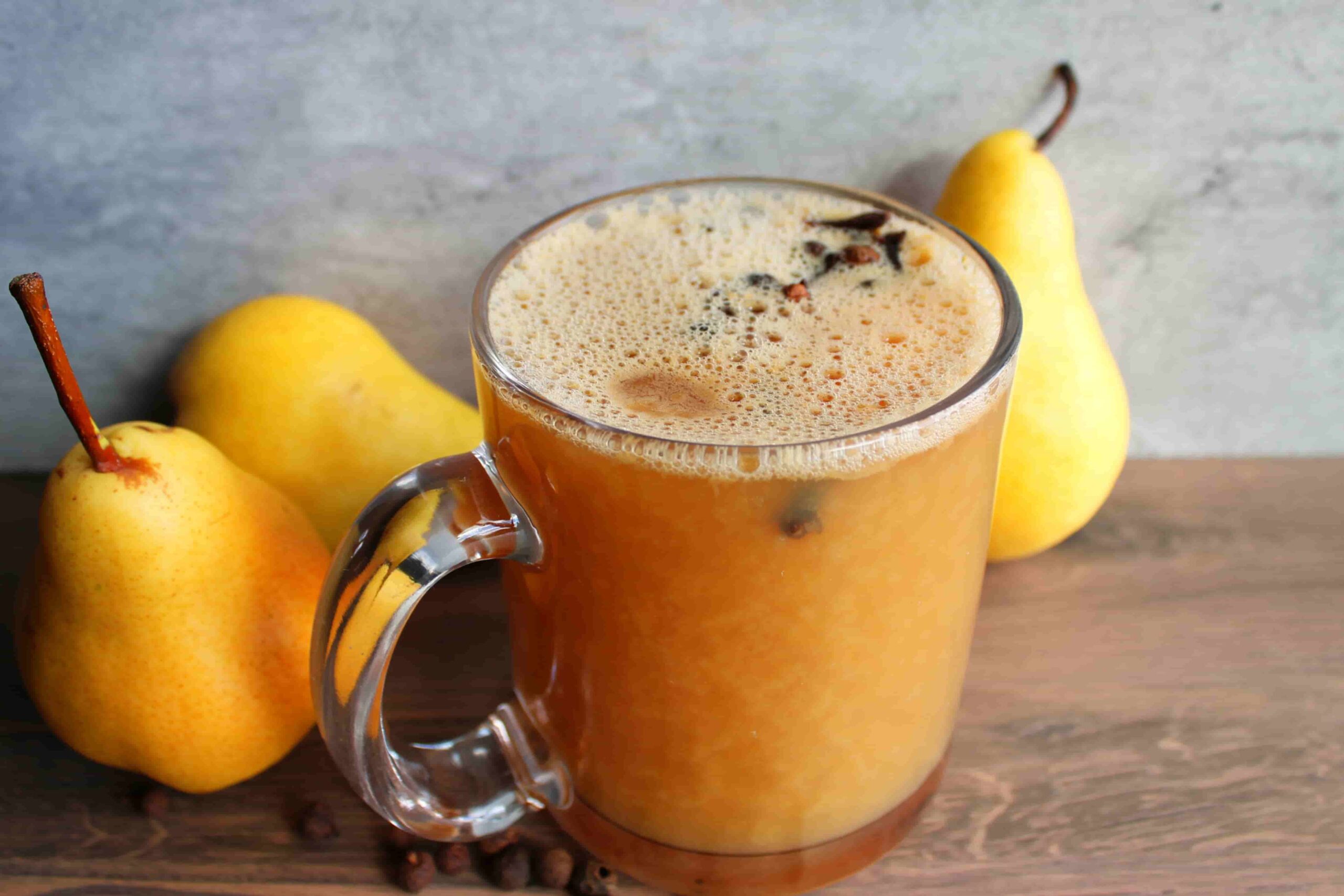homemade spiced pear cider in glass mug with pears