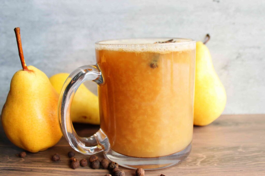 homemade hot pear cider in mug with pears on side