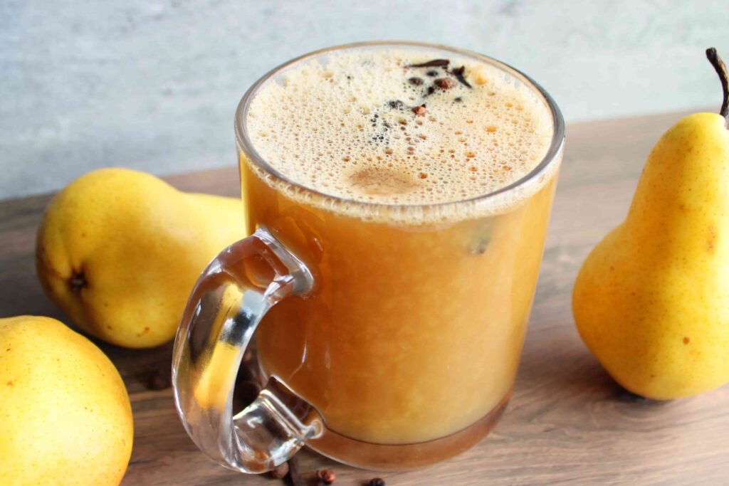 hot pear cider in mug with spices and fresh pears