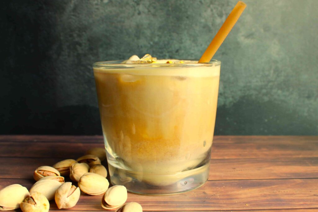 iced pistachio latte homemade in glass with pistachios on the side
