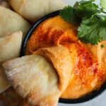 roasted red pepper hummus no tahini in bowl with pita dipped in